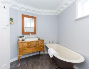 a bathroom with a tub and a sink and a mirror at Harrison House in Featherston
