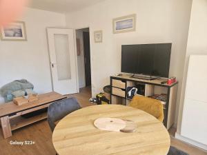 a living room with a table and a flat screen tv at Studio 2 personnes in Cucq