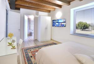 a white bedroom with a bed and a window at Alla Corte del Gallo in Tricesimo