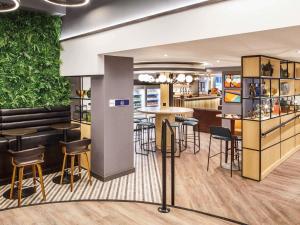 a restaurant with a bar with stools and tables at ibis budget Swindon Town Centre in Swindon