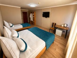a hotel room with two beds and a television at DEMAL Mountain Resort in Alamedin