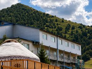 a large building with a hill in the background at DEMAL Mountain Resort in Alamedin