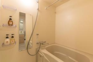 a bathroom with a tub and a shower with a mirror at NOVI Dotonbori in Osaka +53 photos