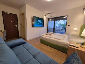 a bedroom with a bed and a couch and a tv at Gargamelo Pension in Poreč
