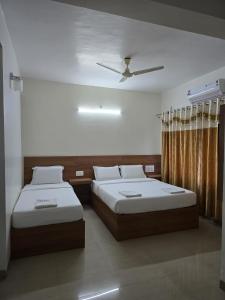 a bedroom with two beds and a ceiling fan at Kukke Sai Skanda in Subrahmanya