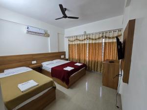 a bedroom with two beds and a flat screen tv at Kukke Sai Skanda in Subrahmanya +12 photos