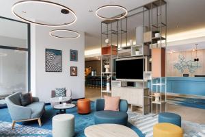 a lobby with chairs and a flat screen tv at Spark by Hilton Essen City Centre in Essen