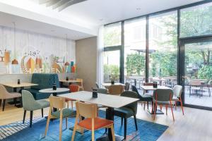 a restaurant with tables and chairs and windows at Spark by Hilton Essen City Centre in Essen