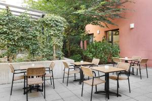 a patio with tables and chairs in front of a building at Spark by Hilton Essen City Centre in Essen