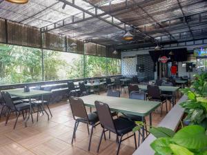 a restaurant with green tables and chairs and windows at RedDoorz Plus @ Karangploso in Karangploso
