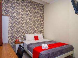 a small bedroom with a bed with a red blanket at RedDoorz Plus @ Karangploso in Karangploso +29 photos