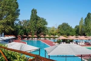 a large swimming pool with umbrellas and a resort at Camping La Chiocciola a Capannole in Capannole