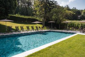 a large swimming pool with chairs and umbrellas at Hotel Flötscherhof in Natz-Schabs