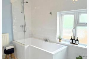 a white bath tub in a bathroom with a window at Walton Beach 1-Bed Cottage Sleeps 2 with Parking in Walton-on-the-Naze