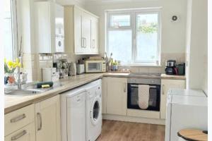 a white kitchen with a sink and a dishwasher at Walton Beach 1-Bed Cottage Sleeps 2 with Parking in Walton-on-the-Naze