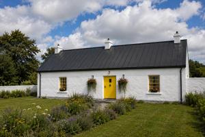 a white house with a yellow door in a yard at Donegal Oceanview Retreat in Drumaville
