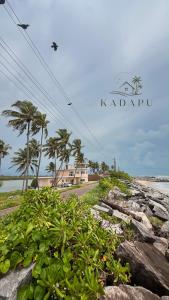 a sign for kiapu with a beach and palm trees at Kadapu stay in Udiyāvara +12 photos