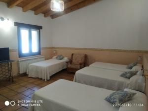 a bedroom with two beds and a chair and a window at Don Camino in Villalcázar de Sirga