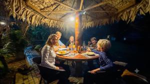 a group of people sitting around a table in a restaurant at Rainforest Royal Heritage in Deniyaya