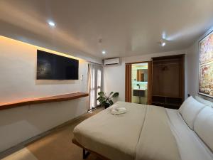 a bedroom with a large white bed and a flat screen tv at Island Pod in El Nido