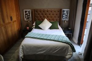 a bedroom with a large bed with green pillows at Blue Crane Luxury Accommodation in Welkom