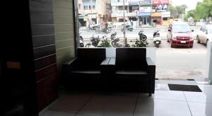 a black couch sitting in front of a window at Hotel Jasmine in Ahmedabad +32 photos