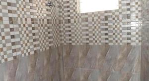 a bathroom with a shower with brown and white tiles at Hotel Jasmine in Ahmedabad
