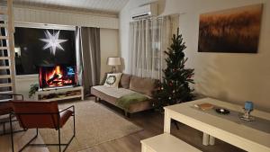a living room with a christmas tree in front of a fireplace at Villa Jokiranta Northern light Riverside in Ranua +59 photos