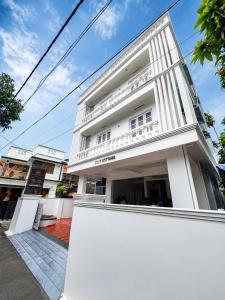 a white building with a fence in front of it at Aura Suites Chernallur in Ernakulam