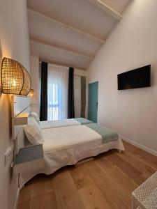 a bedroom with a large bed and a flat screen tv at O Legado de Ramira in Villanueva de Arosa