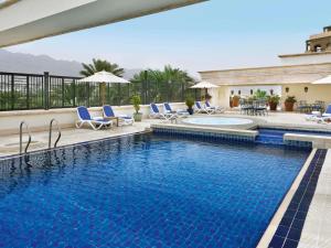 a swimming pool with blue chairs and a swimming poolvisor at Mövenpick Resort & Residences Aqaba in Aqaba