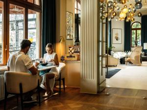 a man and woman sitting at a table in a restaurant at Rezydent Hotel Sopot - MGallery Collection in Sopot +269 photos