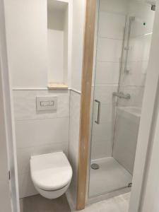 a white bathroom with a toilet and a shower at Appartement cosy in Les Rousses