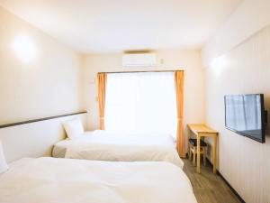 a hotel room with two beds and a window at コンドミニオ久貝 in Miyako-jima