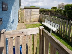 a wooden fence with a bench next to a building at Idyllic, Luxurious Seaside Flat for 4. in Borth