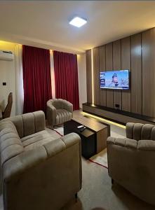 a living room with couches and a flat screen tv at Rivona Hotels & Suites in Uyo