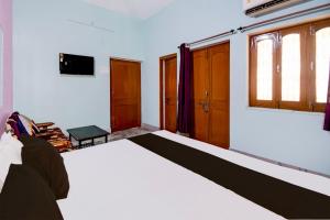 a bedroom with a bed and a tv on the wall at Hotel O Magadh Guest House in Gaya