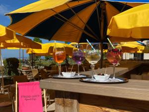 four glasses of wine sitting on a table under an umbrella at Hotel Strand-Café mit Gästehaus Charlotte in Langenargen