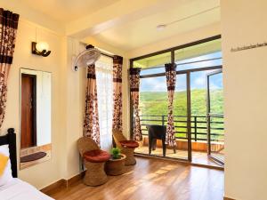 a bedroom with a large window and a balcony at Cloud Valley Inn in Cherrapunji