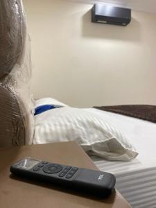 a remote control sitting on a table next to a bed at City Haven Faisalabad in Faisalabad
