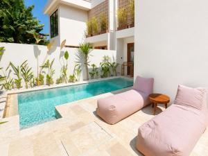 a swimming pool in a house with a pink couch at Oasis Dune Villas Lombok in Kuta Lombok