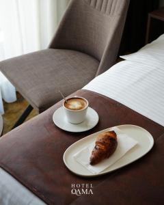 a cup of coffee and a piece of food on a table at Qama Hotel in Prishtinë
