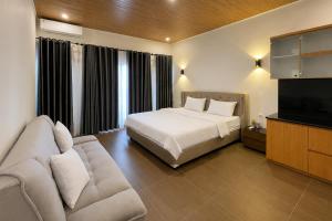 a bedroom with a bed and a couch and a television at The Lavana Hotel Florida Kuta Mandalika in Kuta Lombok