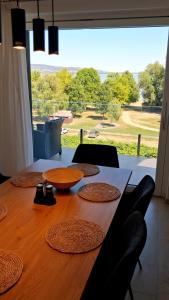 a wooden table with chairs and a large window at Helikon Terasz Apartman in Keszthely