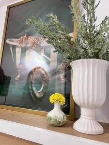 a white vase sitting on a shelf next to a vase with flowers at Ραστώνη in Tolo