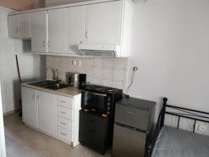 eine kleine Küche mit weißen Schränken und einer schwarzen Mikrowelle in der Unterkunft Elias Appartment in Volos