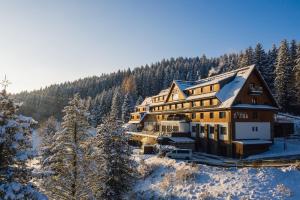 a large building in the snow with trees at Grandhotel Tatra in Velké Karlovice