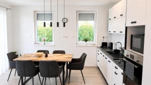 a white kitchen with a wooden table and chairs at Helikon Terasz Apartman in Keszthely