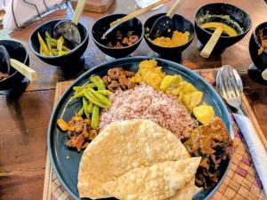 a plate of food with rice and other foods on a table at Rainforest Royal Heritage in Deniyaya +49 photos