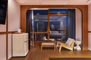 a living room with a refrigerator and a bedroom at Marysol Stay in Busan